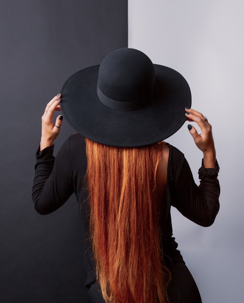 a woman with long red hair wearing a black hat