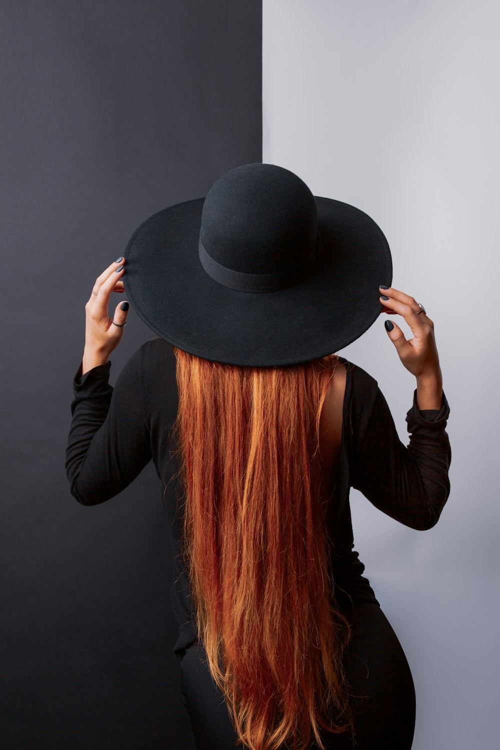 a woman with long red hair wearing a black hat