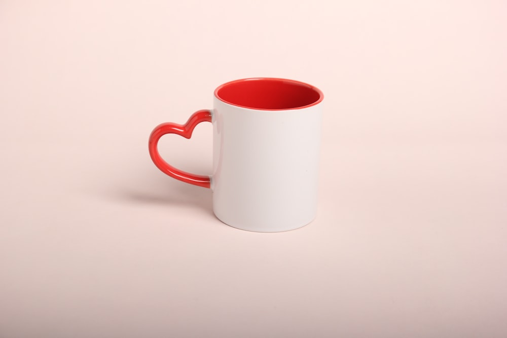 a red and white coffee mug with a heart shaped handle