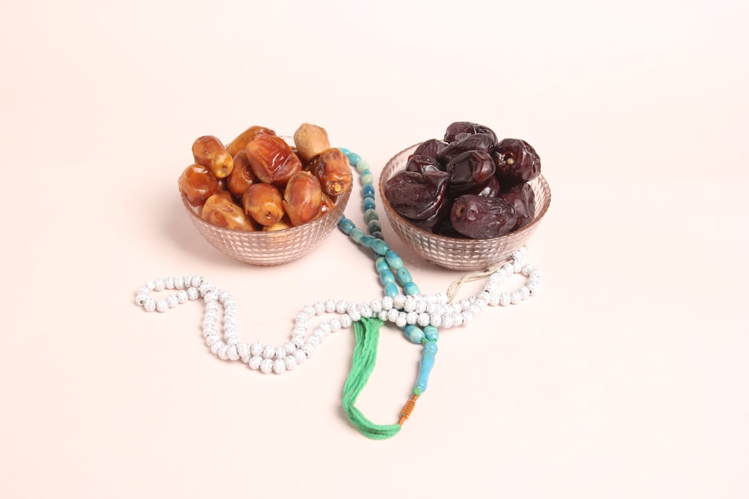Beautiful Dates in cup with prayer Beads photography on light pink background. 