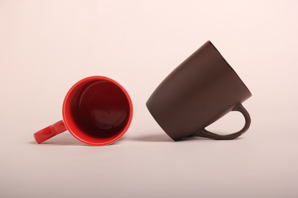 a red and brown coffee cup sitting next to each other