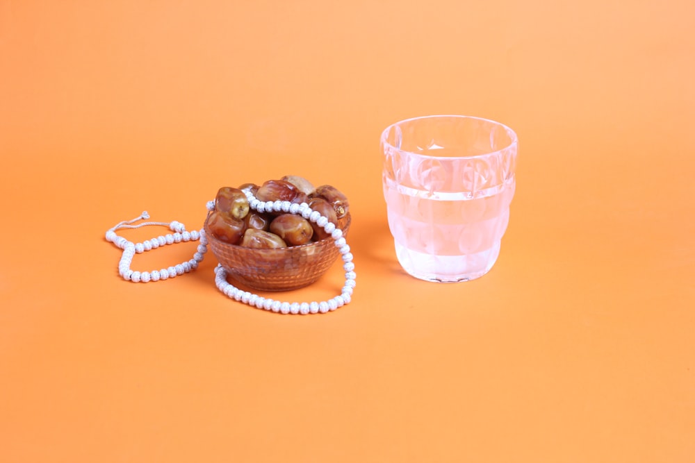 a glass of water next to a beaded bracelet