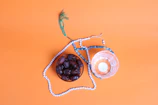 an orange background with a bowl of fruit and a string of beads