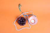 an orange background with a bowl of fruit and a string of beads