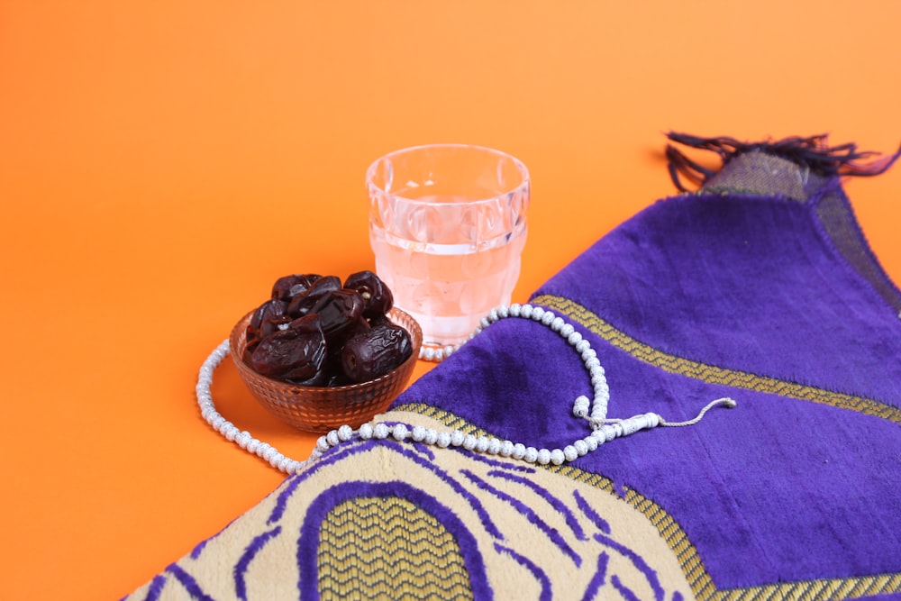 a bowl of raisins next to a glass of water