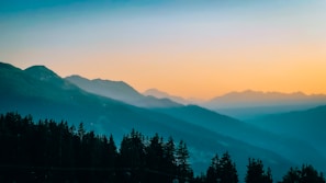 the sun is setting over a mountain range