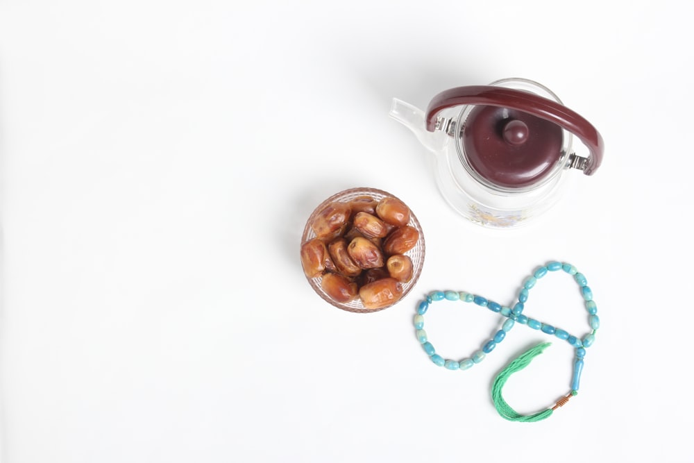 a cup of nuts next to a string of beads