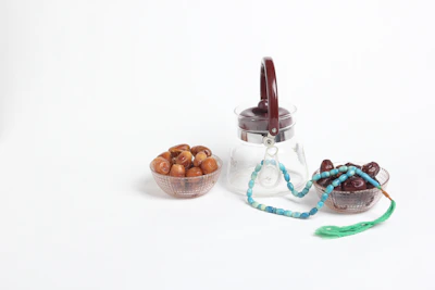 A glass jar of rich, amber date syrup with a wooden spoon dripping syrup, surrounded by fresh dates.