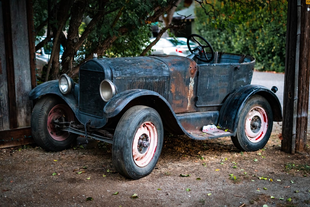 an old car is parked under a tree