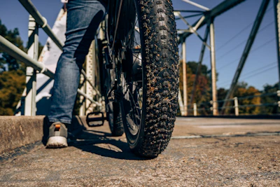 Close-up of a mountain bike tire on a rugged forest path with autumn leaves.