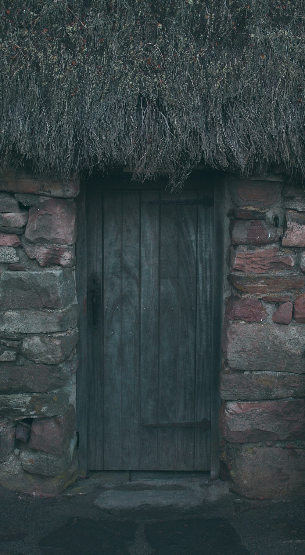 a stone building with a thatched roof and a wooden door