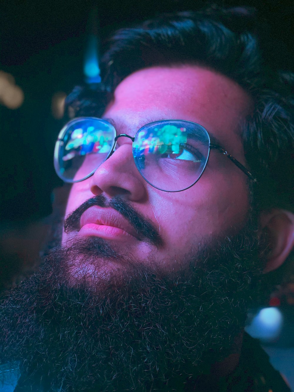 a man with a beard and glasses looking up