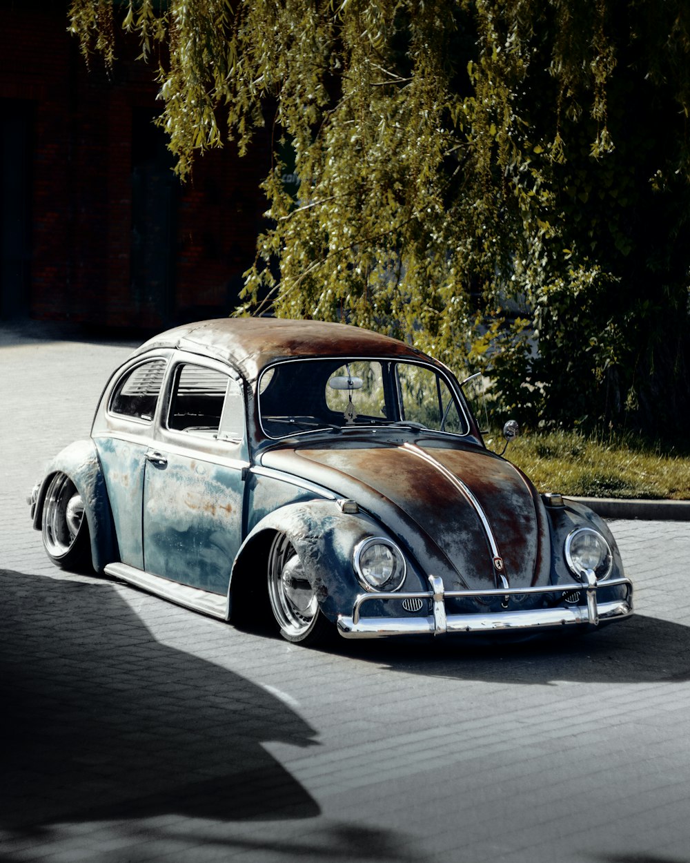 a rusted volkswagen beetle sitting on the side of a road