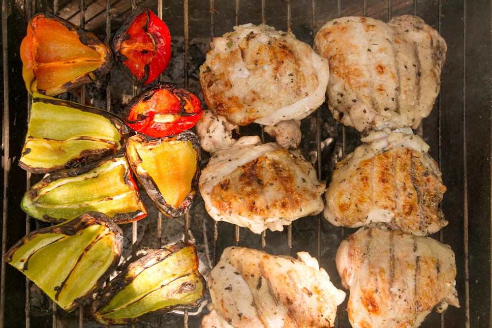 a grill with chicken and vegetables cooking on it