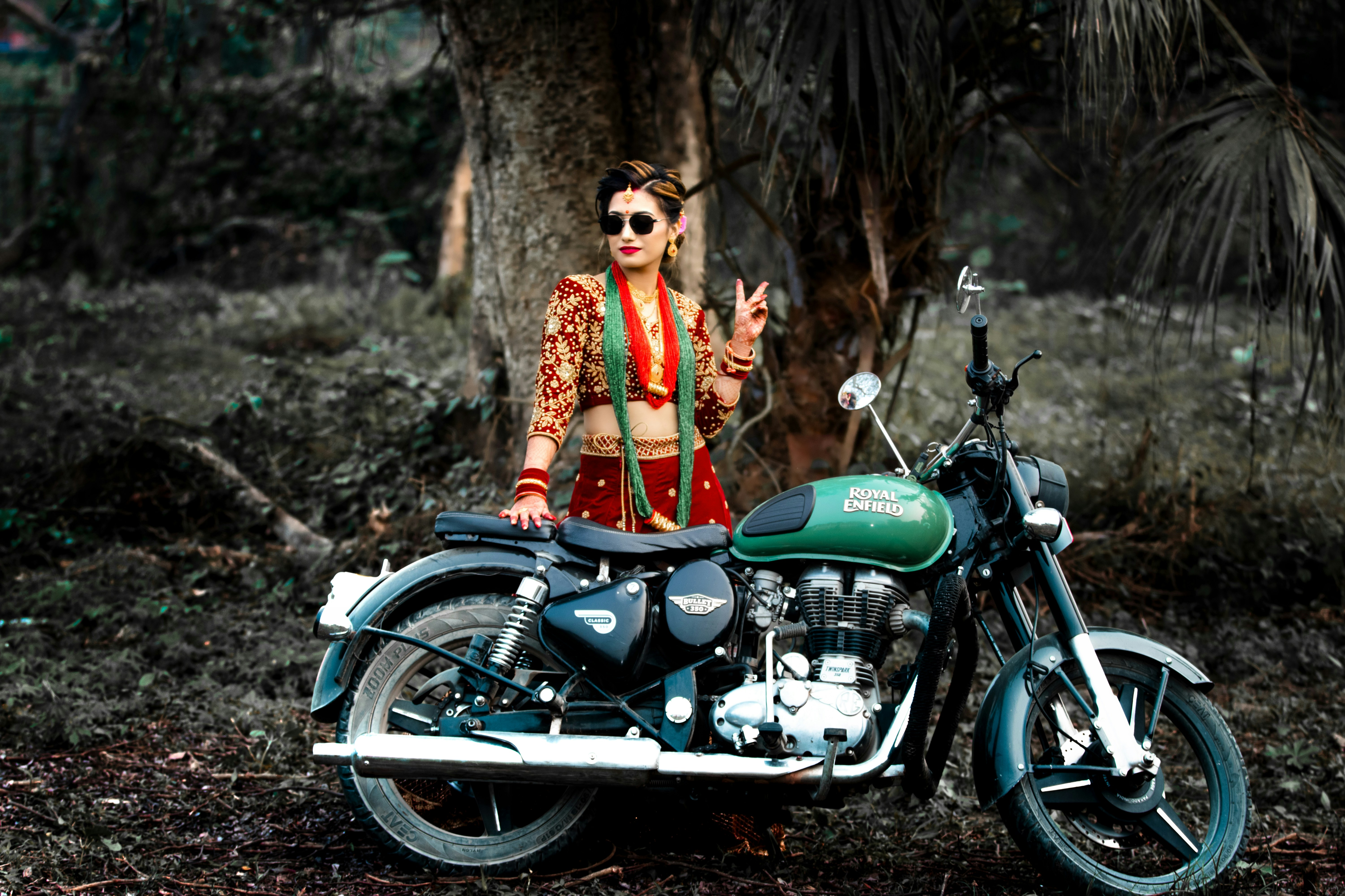 a woman standing next to a motorcycle in the woods