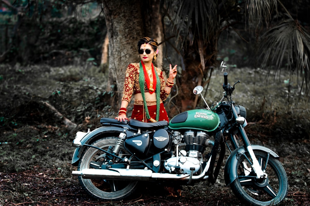 a woman standing next to a motorcycle in the woods