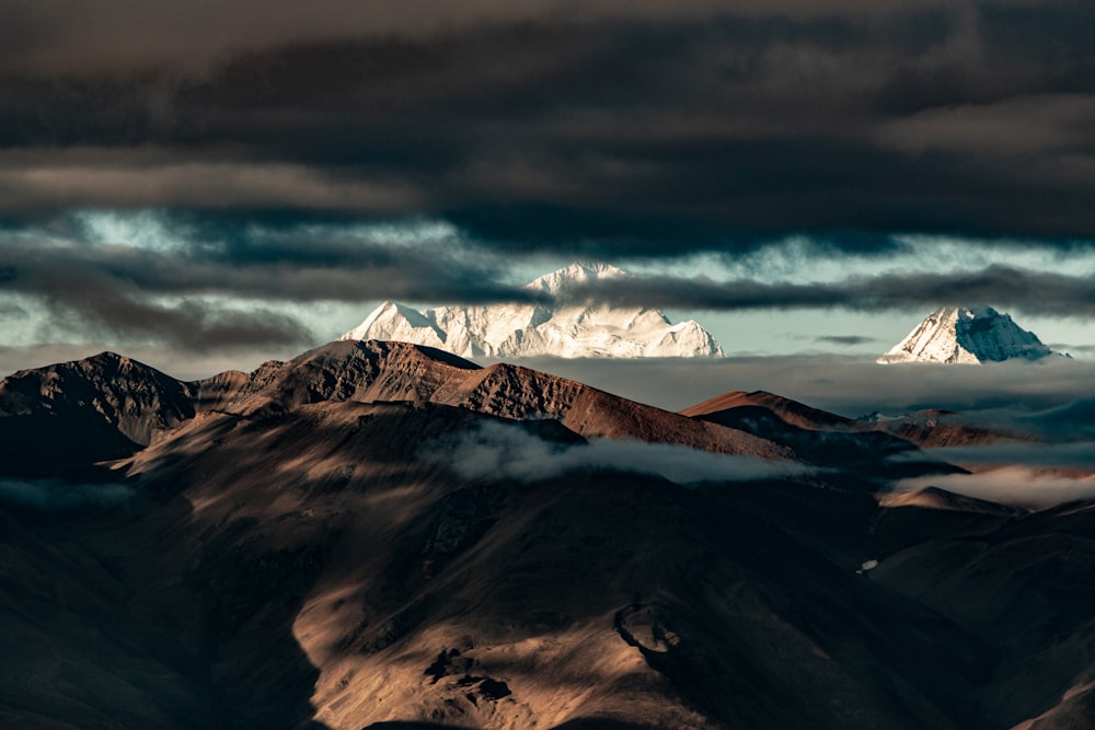 a mountain range covered in clouds under a cloudy sky