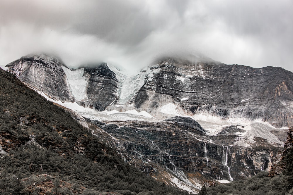 a mountain covered in snow under a cloudy sky