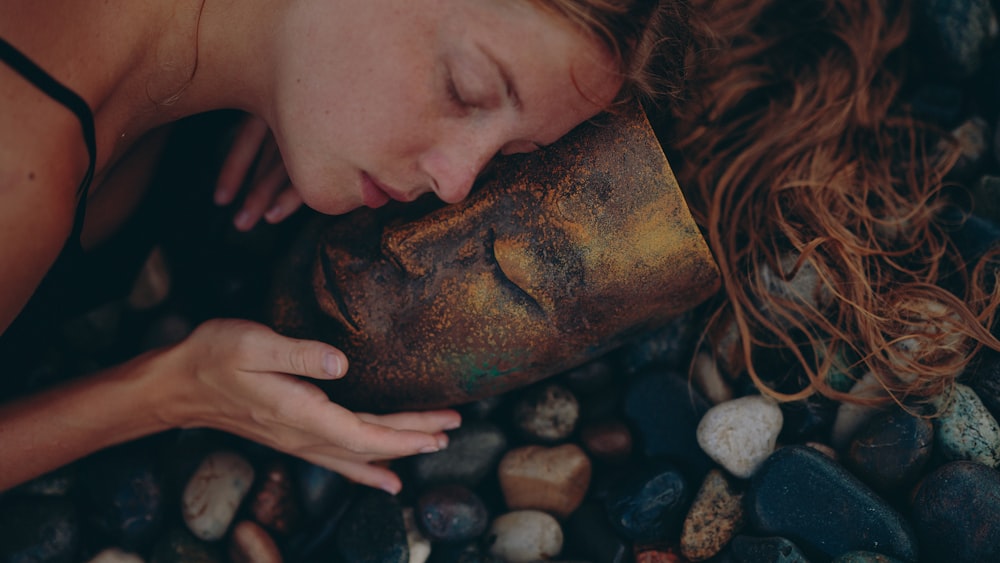 a woman laying on a bed of rocks with her eyes closed