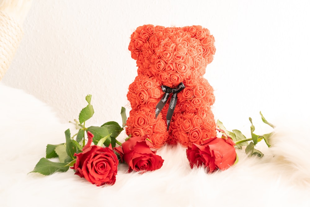 a teddy bear made out of roses sitting on a bed