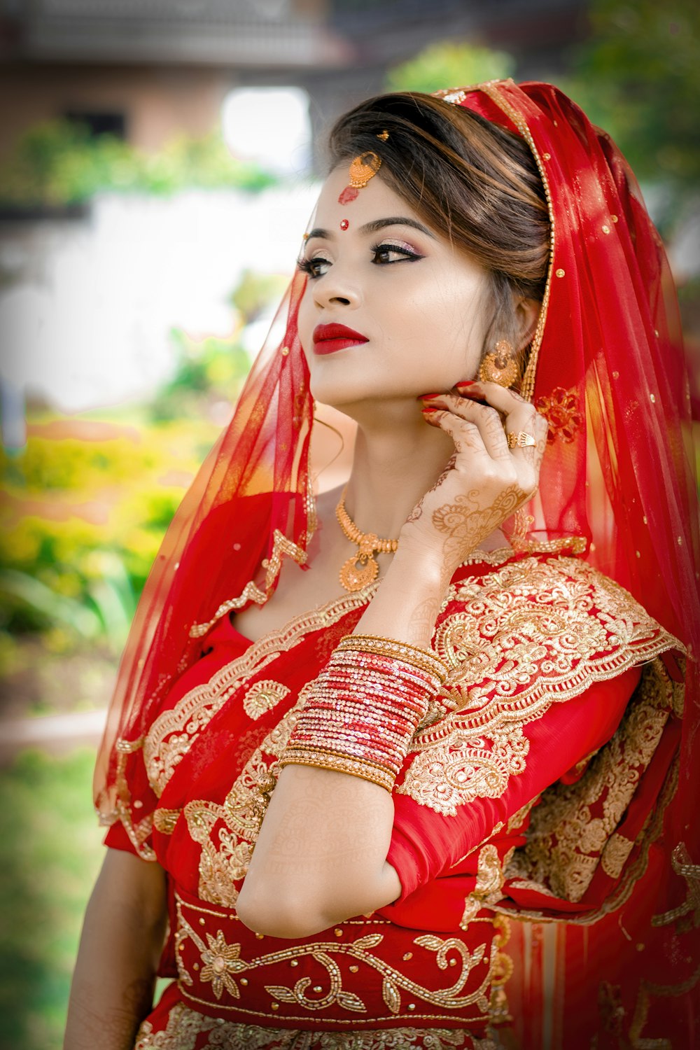 a woman in a red and gold bridal outfit