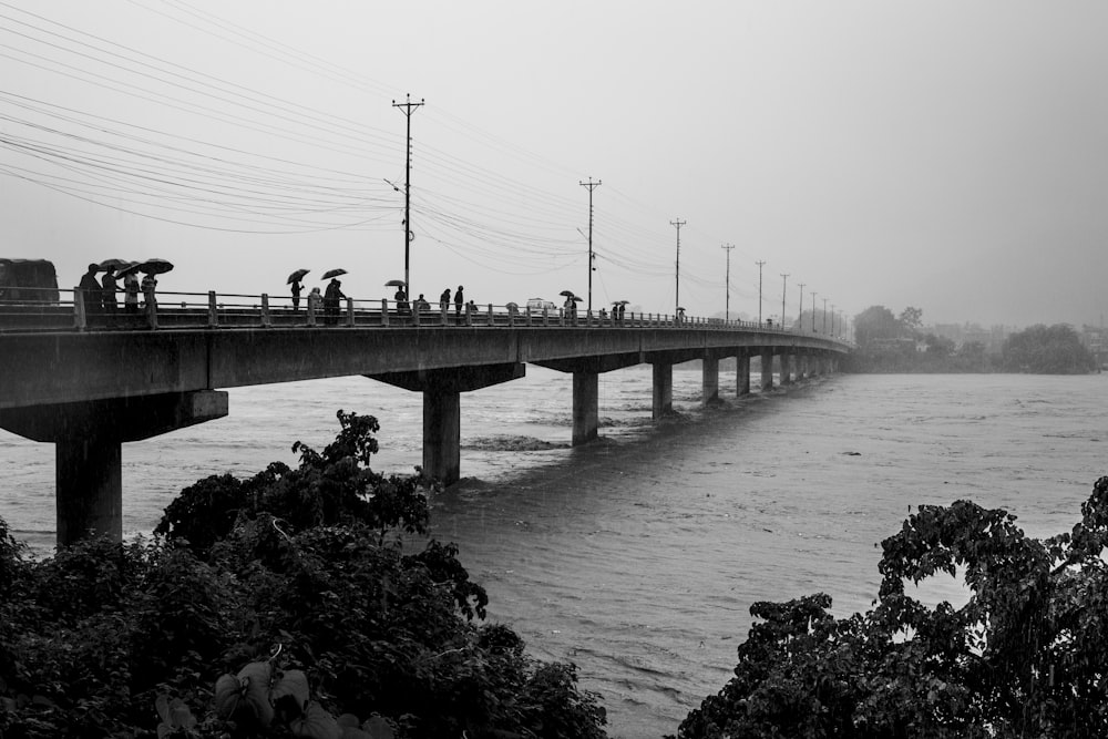 a black and white photo of people on a bridge