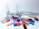 Various colorful pills and ampoules are arranged on a white surface, alongside a transparent measuring tube. The pills include capsules and tablets in colors such as blue, orange, pink, red, and black. The ampoules are made of clear glass, indicating a medical or pharmaceutical theme.
