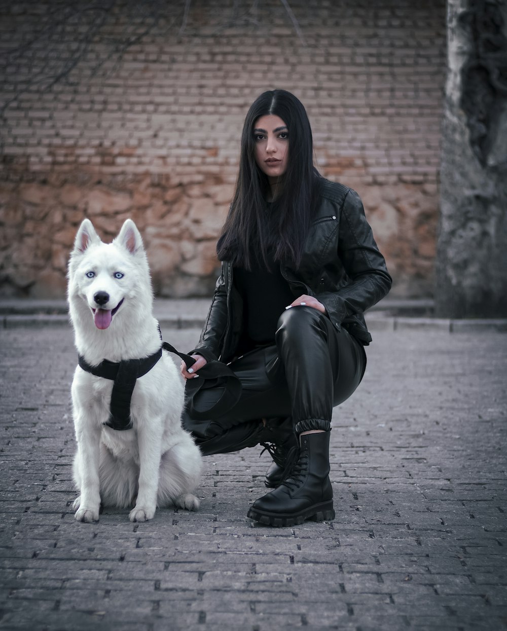 a woman sitting on the ground next to a white dog