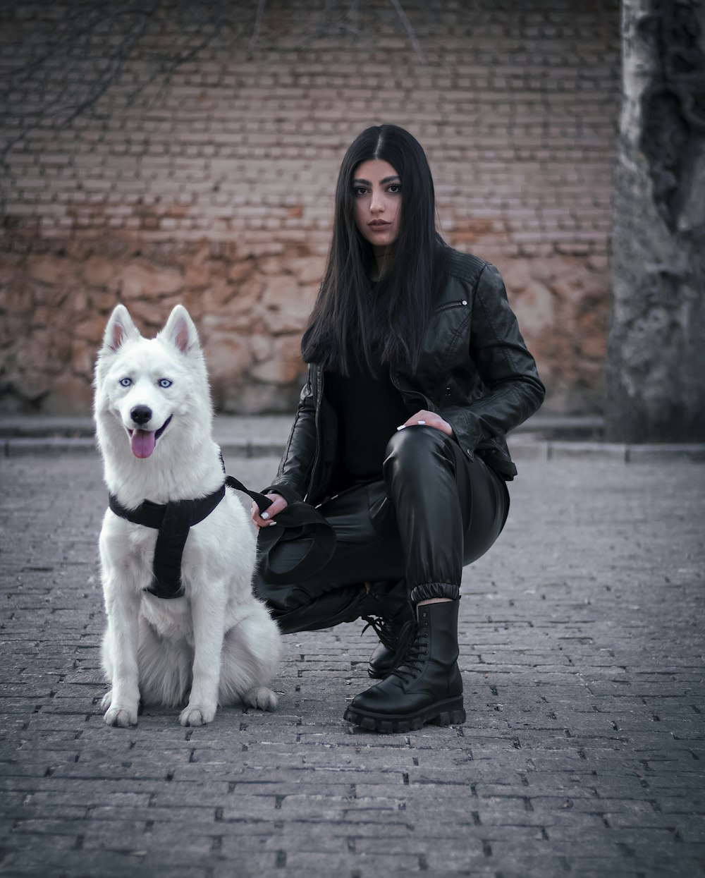 une femme assise par terre à côté d’un chien blanc