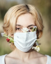 a woman wearing a face mask and flowers in her hair