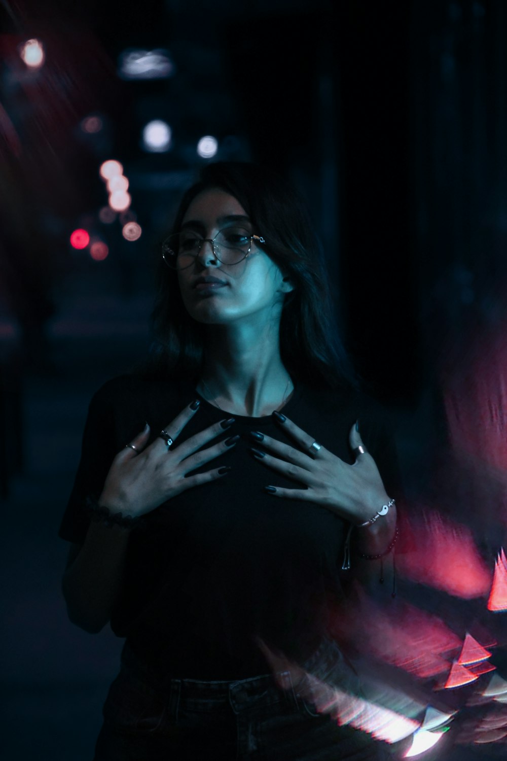 a woman standing in the dark with her hands on her chest
