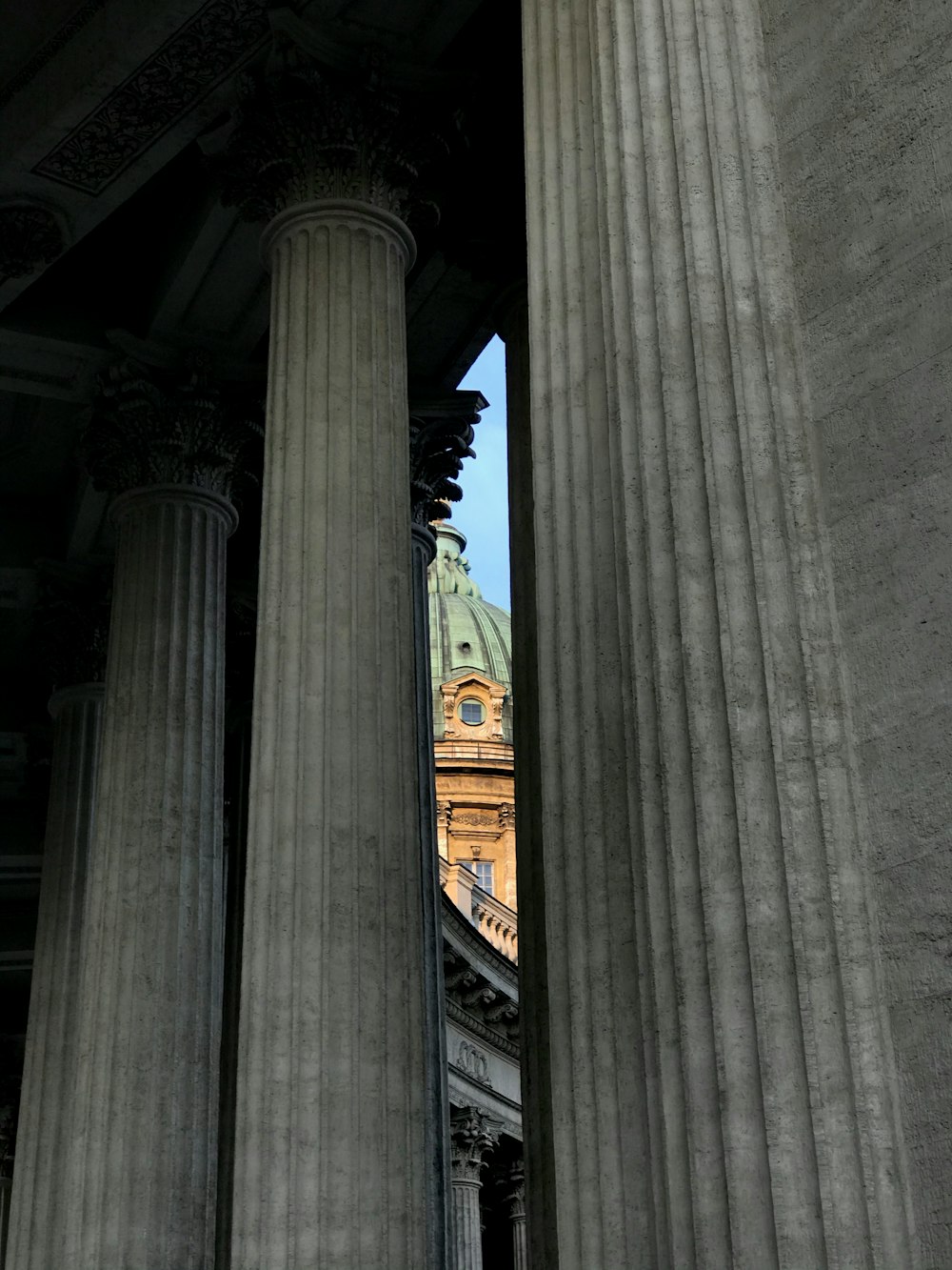 a tall building with columns and a clock tower in the background