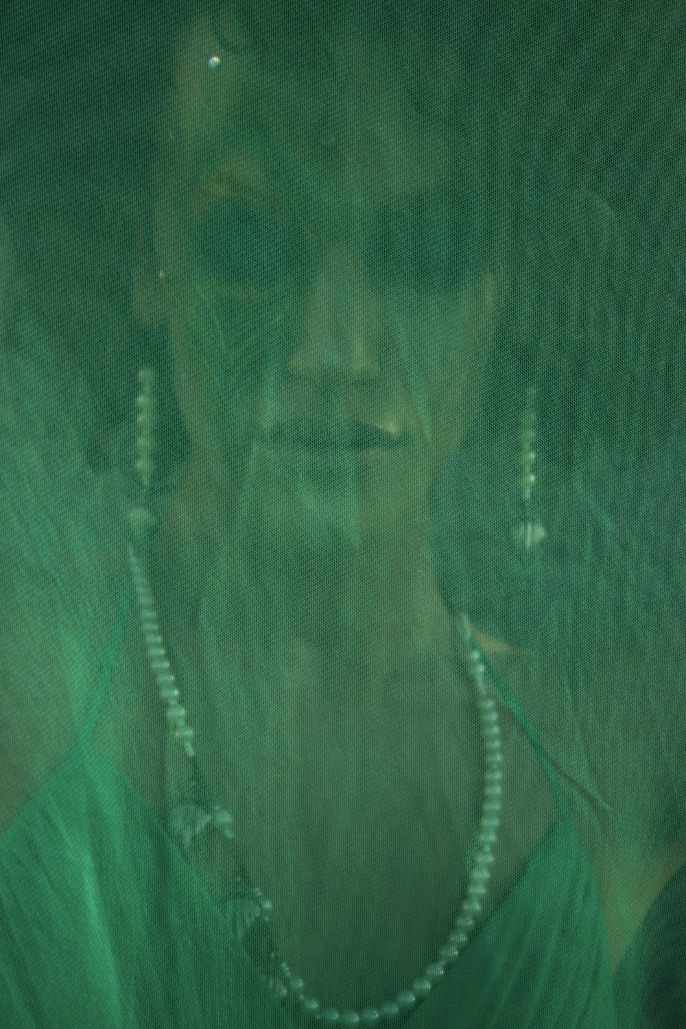 a woman in a green dress with pearls on her necklace