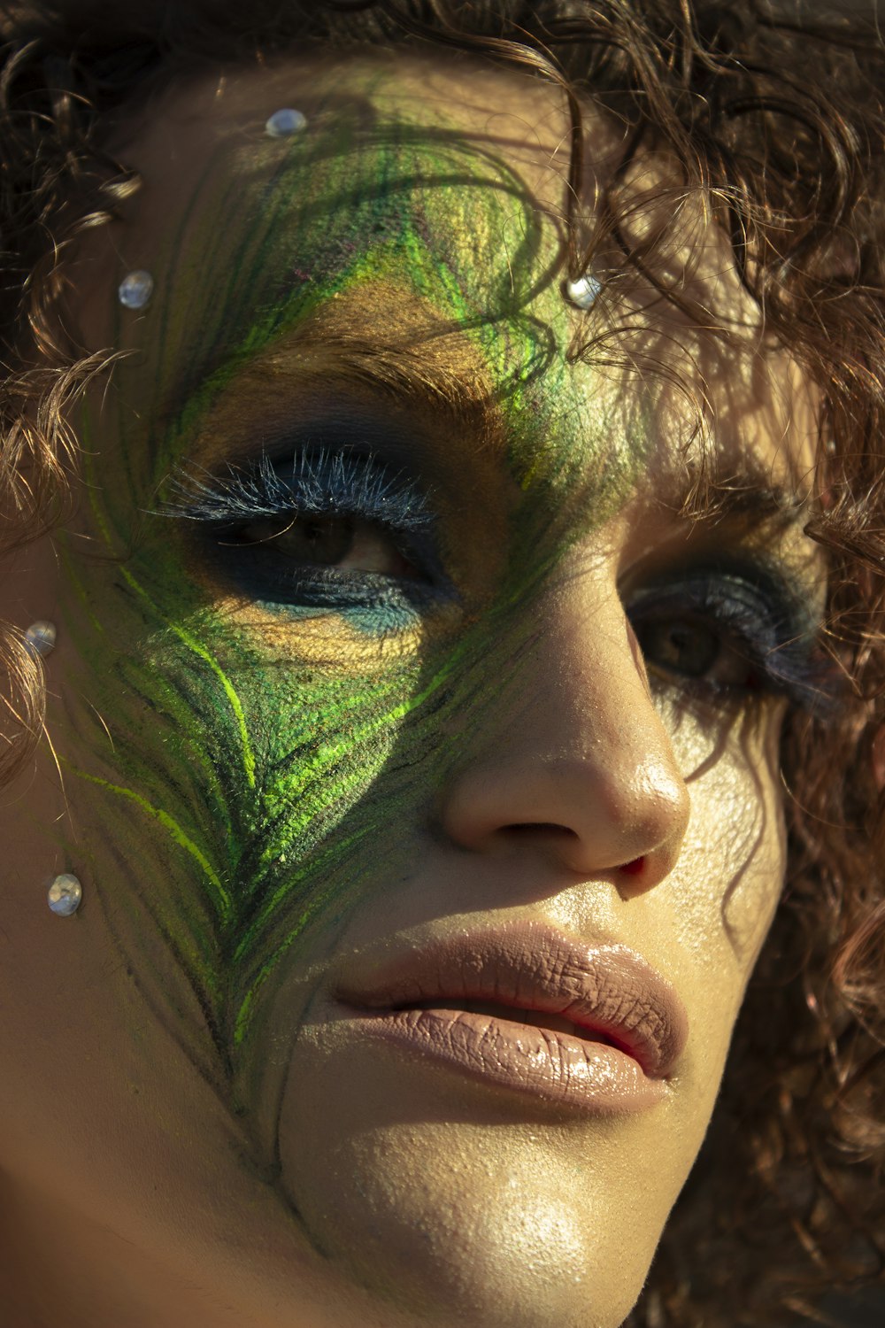 a close up of a woman's face with a green feather painted on her