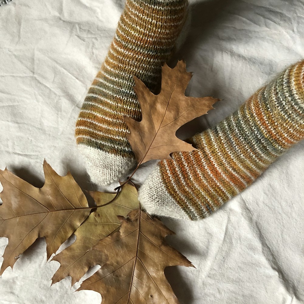 un par de calcetines y una hoja de arce sobre una sábana