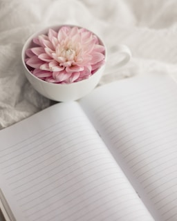 A peaceful moment captured as a person journals beside a cup of herbal tea and fresh flowers.