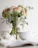 Softly lit white orchid in a minimalist ceramic vase beside an open journal with handwritten notes.