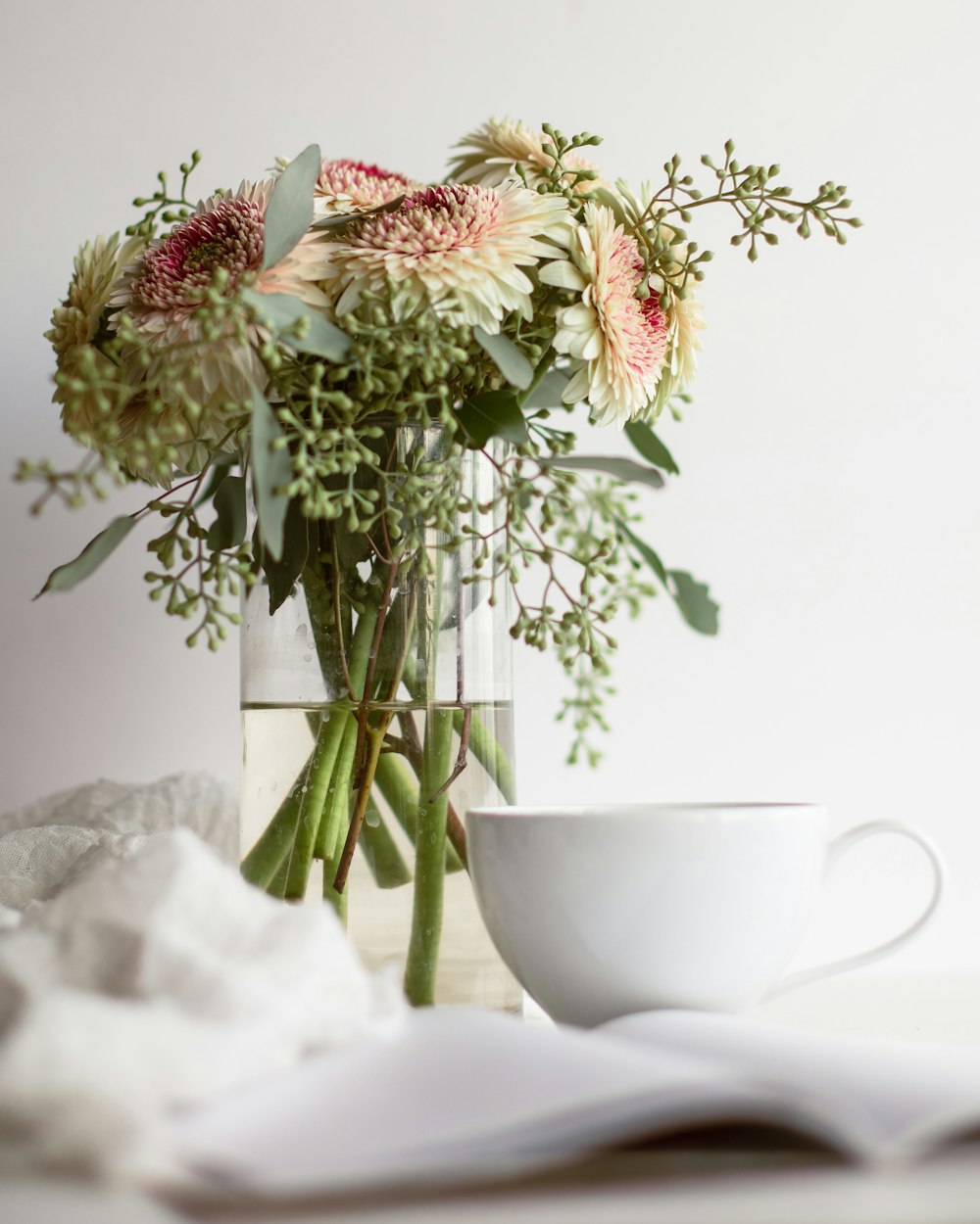 a bouquet of flowers in a vase next to a cup