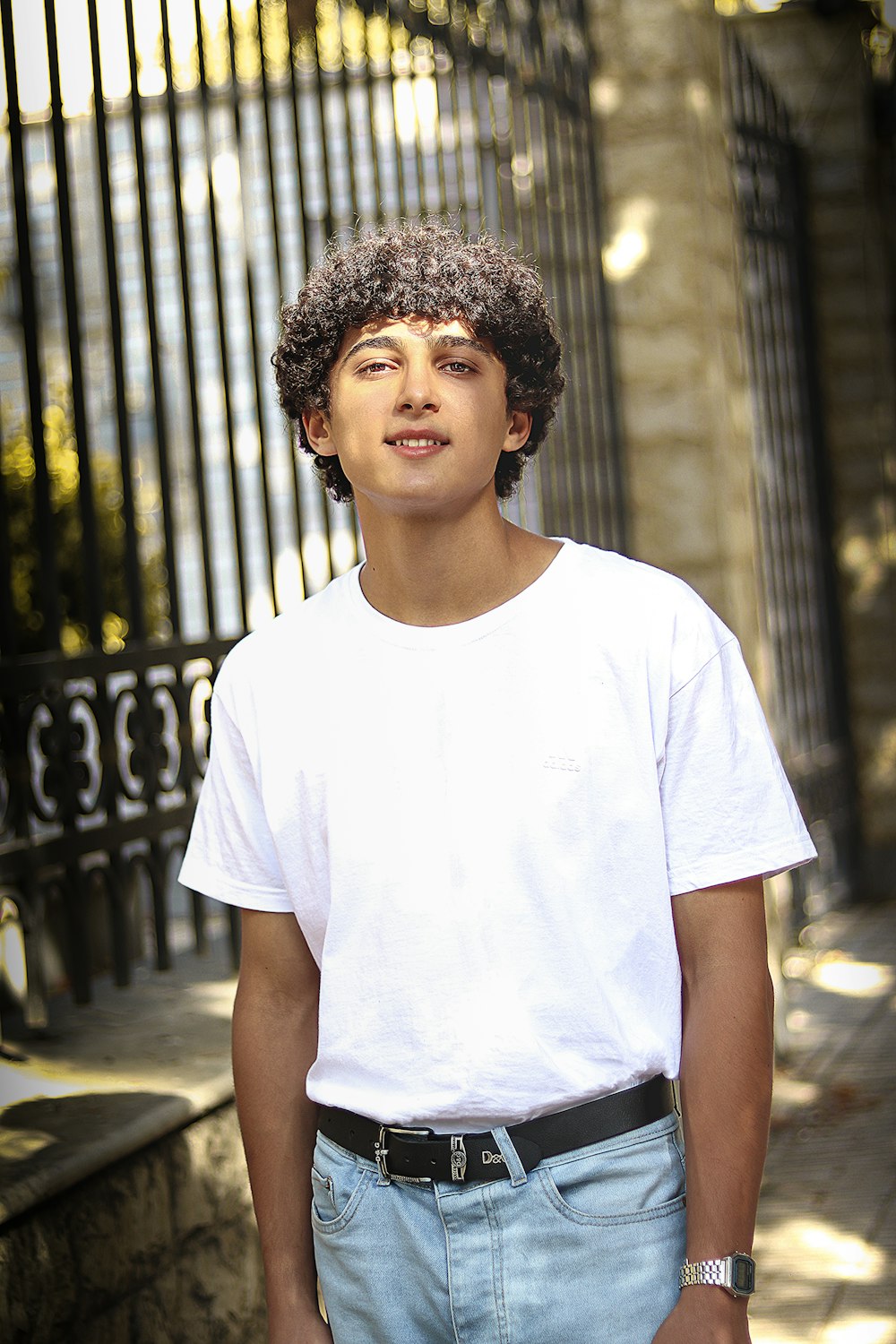 a young man standing in front of a fence