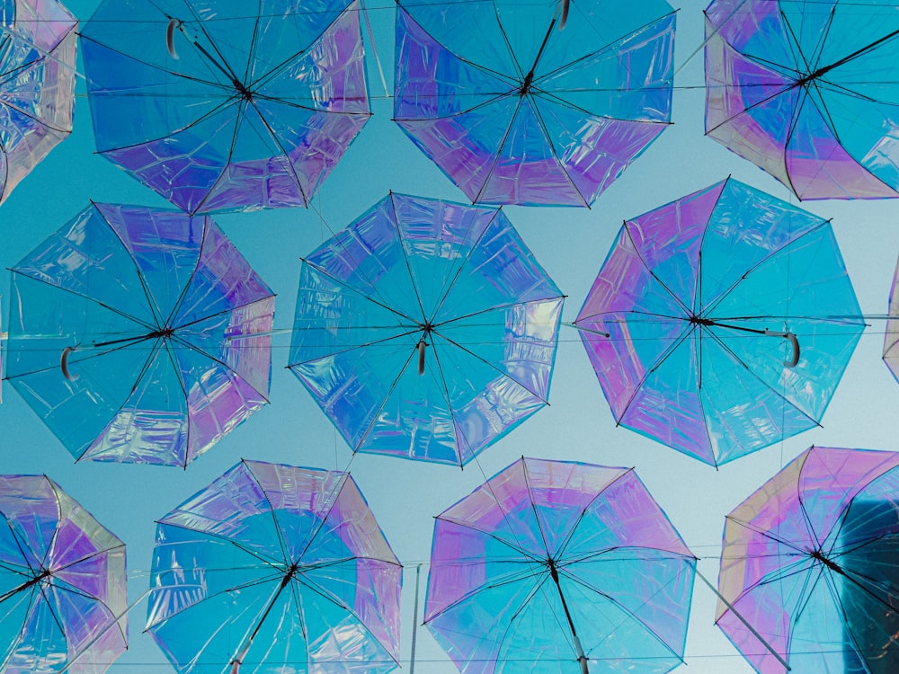 a group of blue and purple umbrellas hanging from a wire