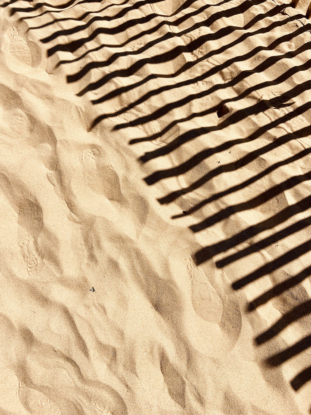 the shadow of a bench on a sandy beach