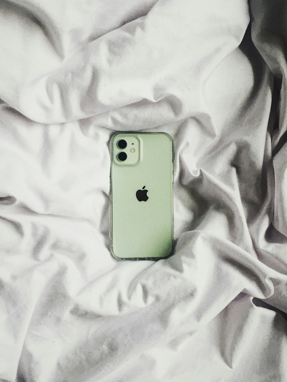 a green iphone case laying on a white sheet
