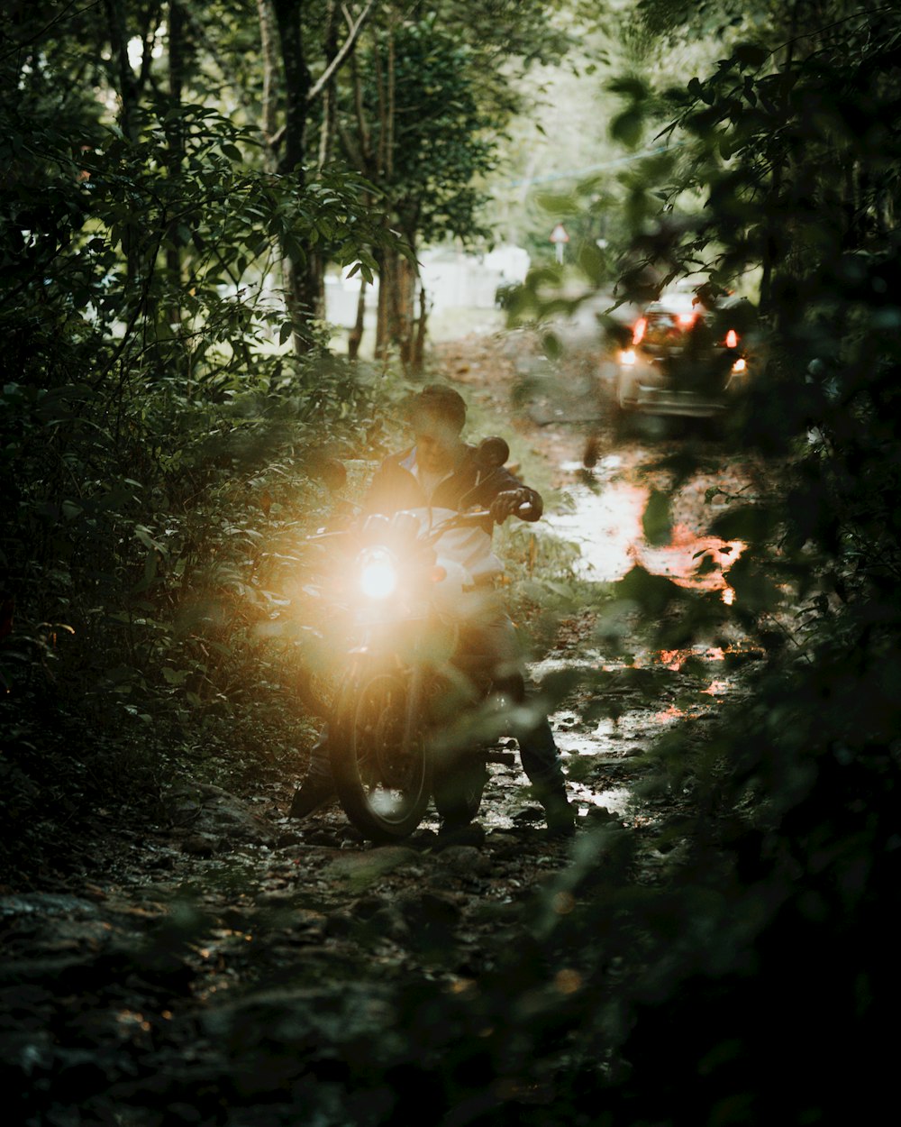 a man riding a motorcycle down a forest road