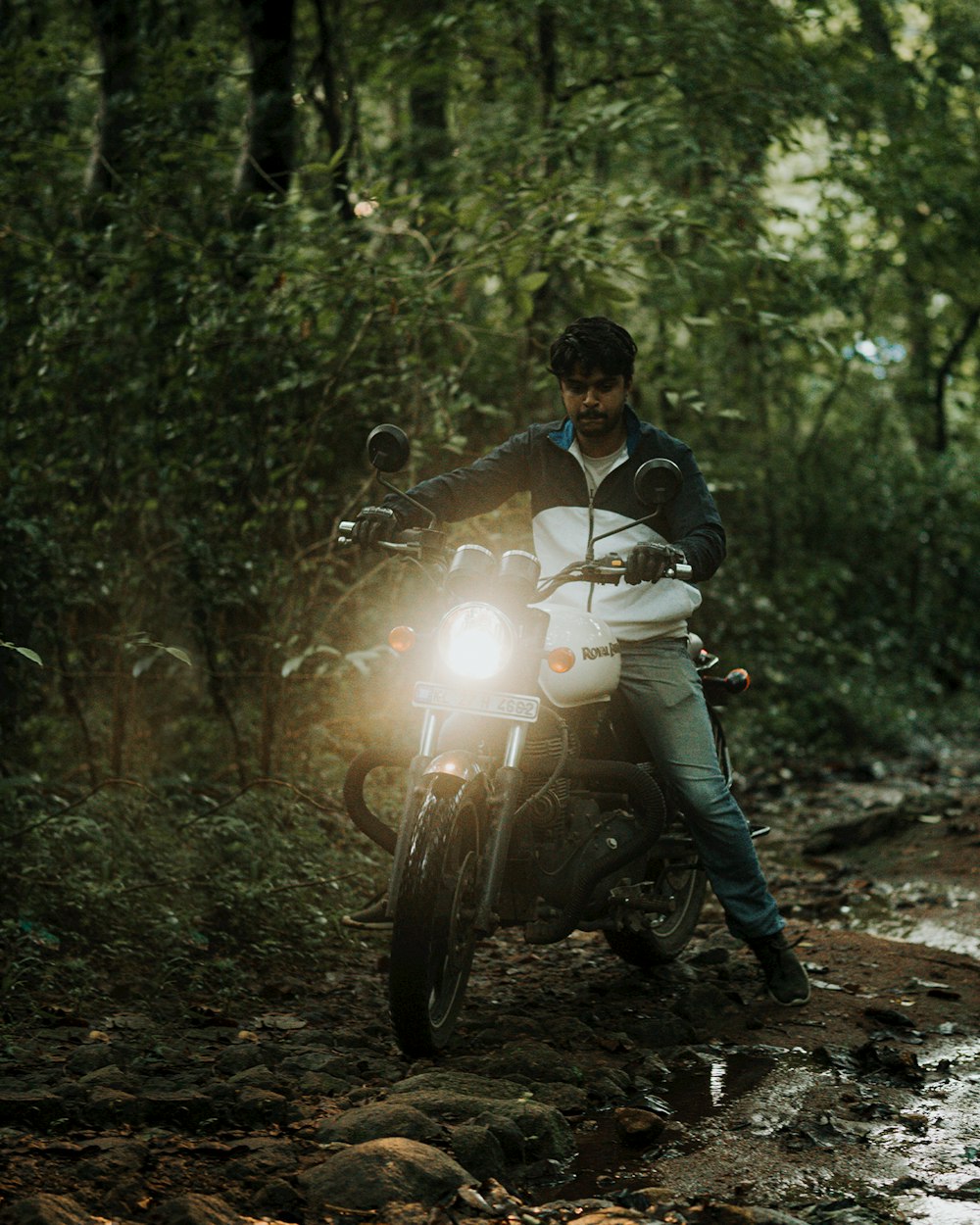 Un hombre conduciendo una motocicleta por un camino fangoso