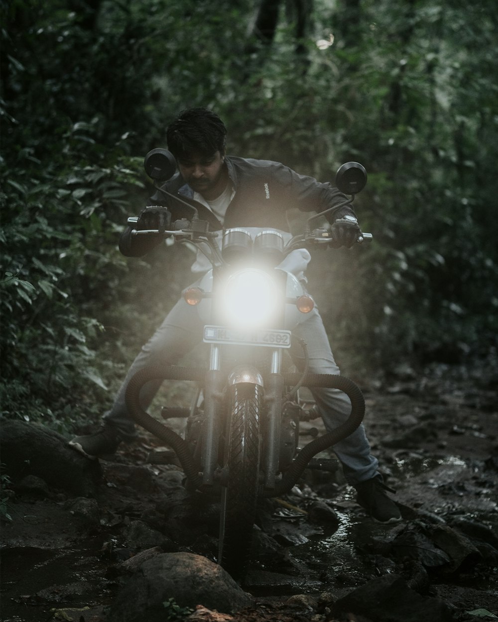 a man riding on the back of a motorcycle through a forest