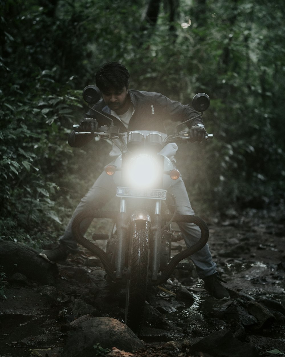 Un hombre montado en la parte trasera de una motocicleta a través de un bosque