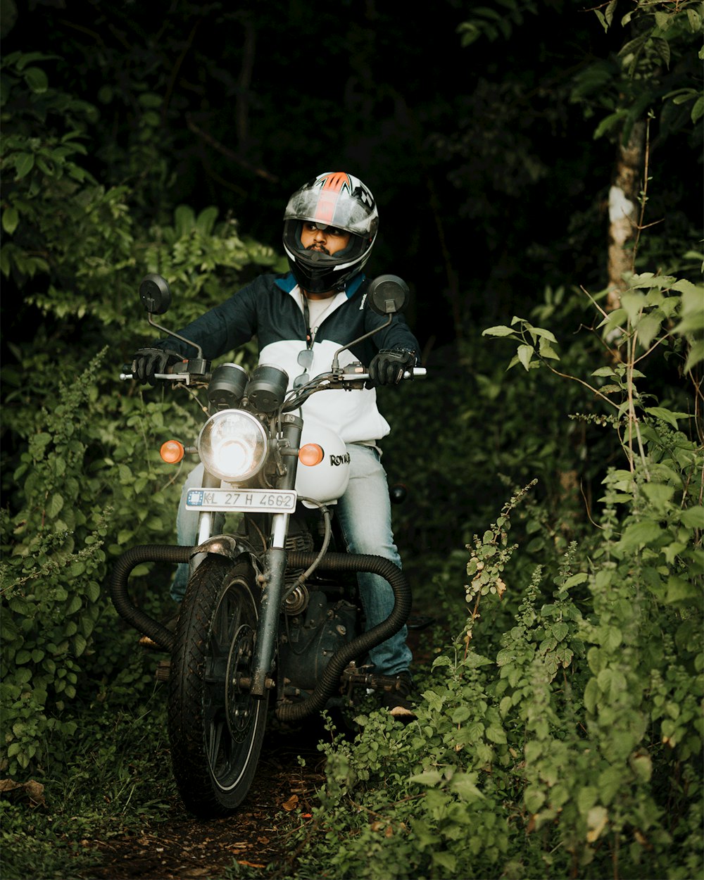 a man riding on the back of a motorcycle through a forest