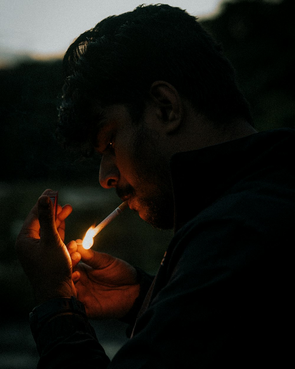 a man holding a lit cigarette in his hand