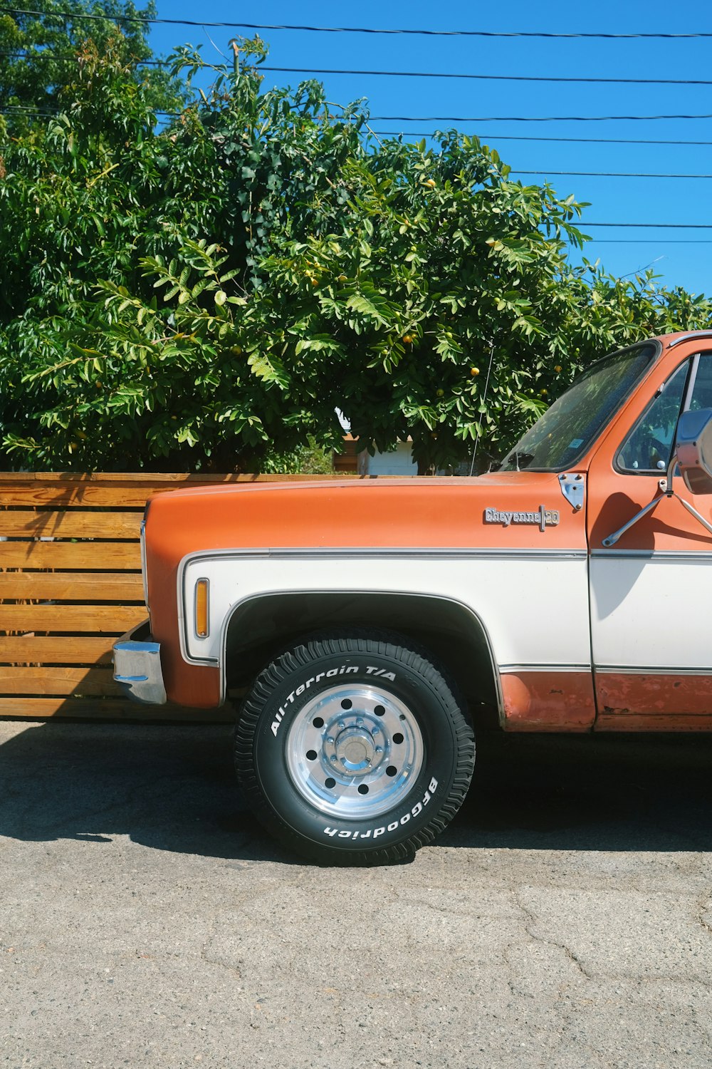 un camion orange et blanc garé à côté d’une clôture en bois