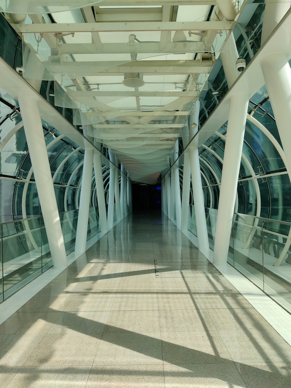 a long hallway with white columns and glass walls